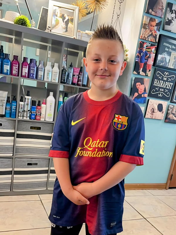 young boy with spiked hair standing in front of product shelf